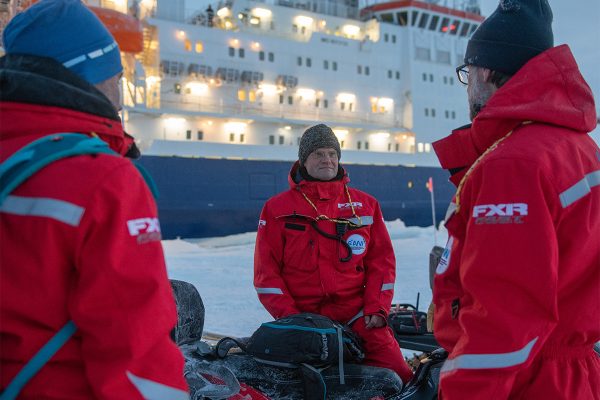 Forschende besprechen eine Expedition im arktischen Eis vor dem Forschungsschiff Polarstern.