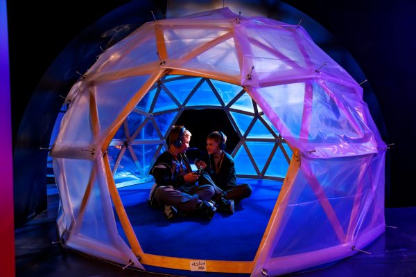 Kinder entdecken mit Audioguides eine Forschungsstation in der Polar Experience Ausstellung über Arktis und Antarktis.